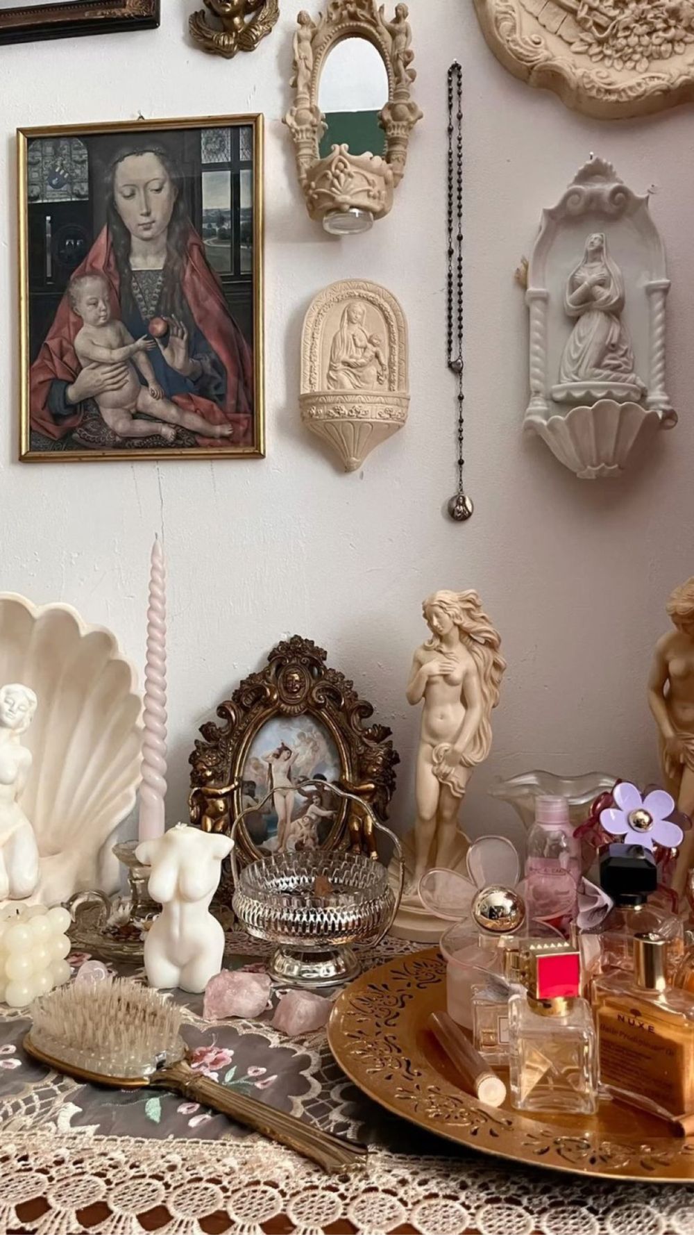 A vanity wall of plaster Madonnas and saints, Venus statues, candles and perfume bottles
